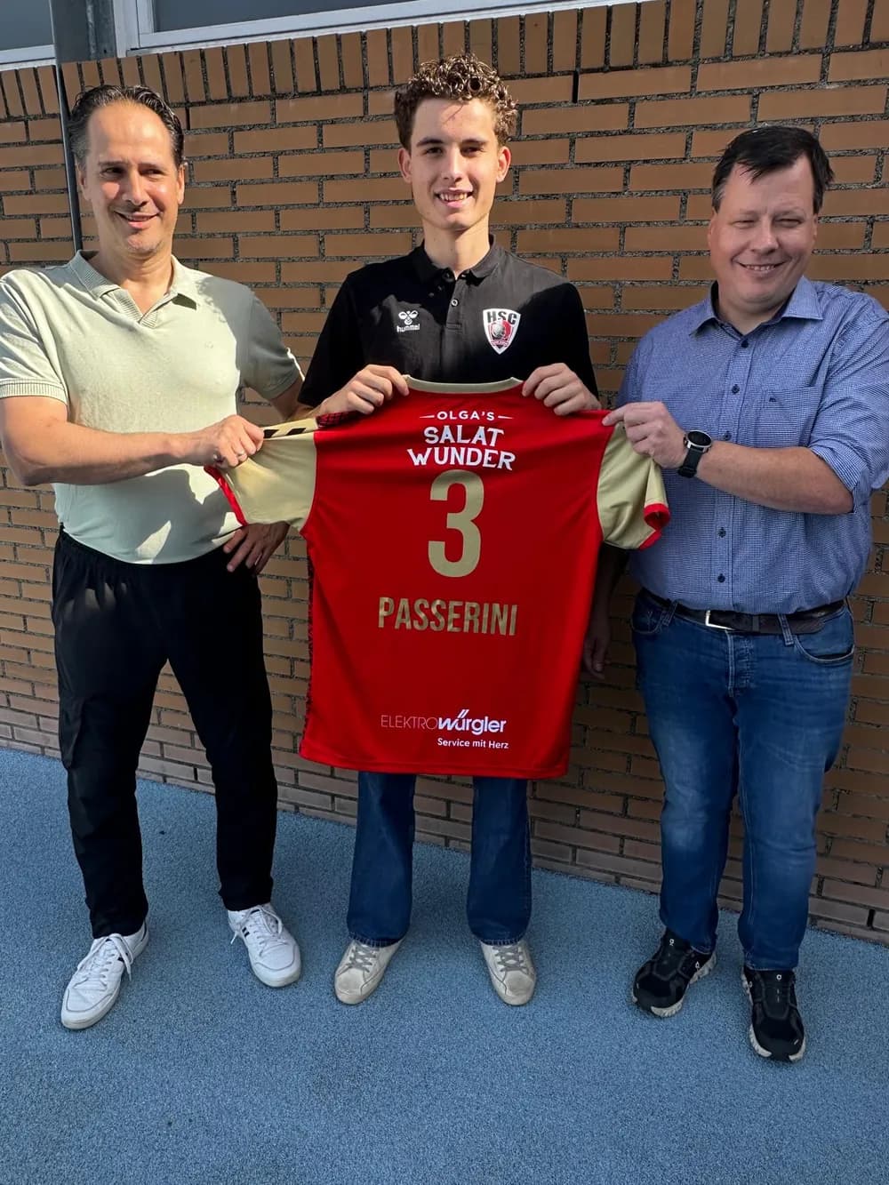 Drei Personen halten das rote Matchtrikot mit dem Logo Olga’s Salatwunder und der Nummer 3 in die Kamera